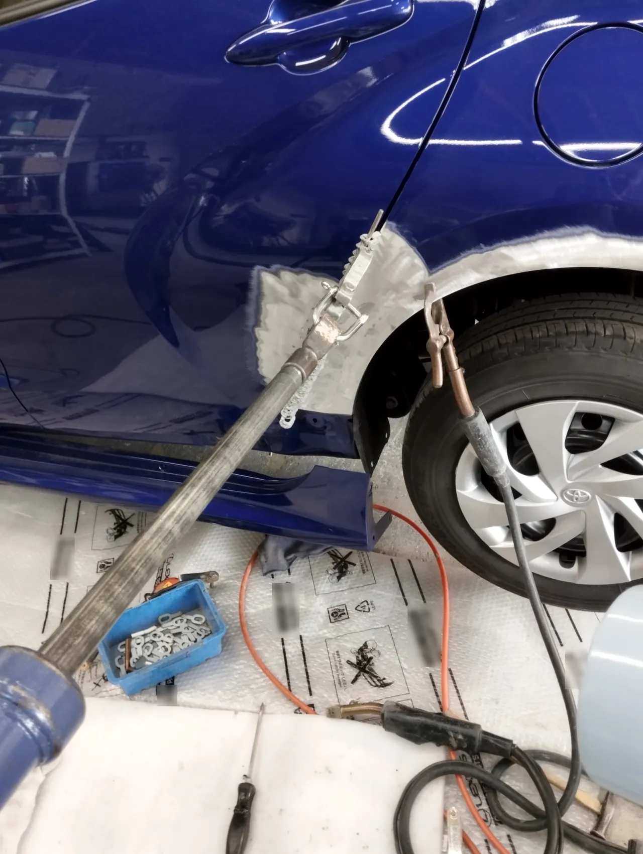ヤリスの左リヤクォーターの前の縁。溶接したワイヤーをくし形の工具で挟み、長いスライドハンマーで外へ引く(引き出し板金)