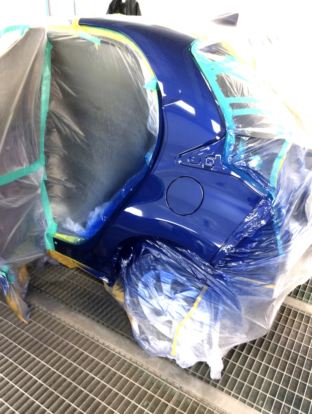 塗装ブースで8W7に塗り上がったヤリスの左リヤクォーター。後輪とドアの開口部はビニールで覆ってある(塗装後)