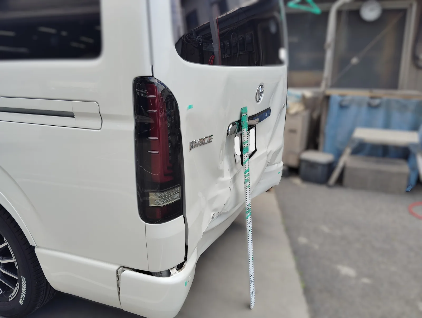 トヨタ・ハイエース 左後ろから見た後部の損傷。スケールを当てて位置と範囲を確認
