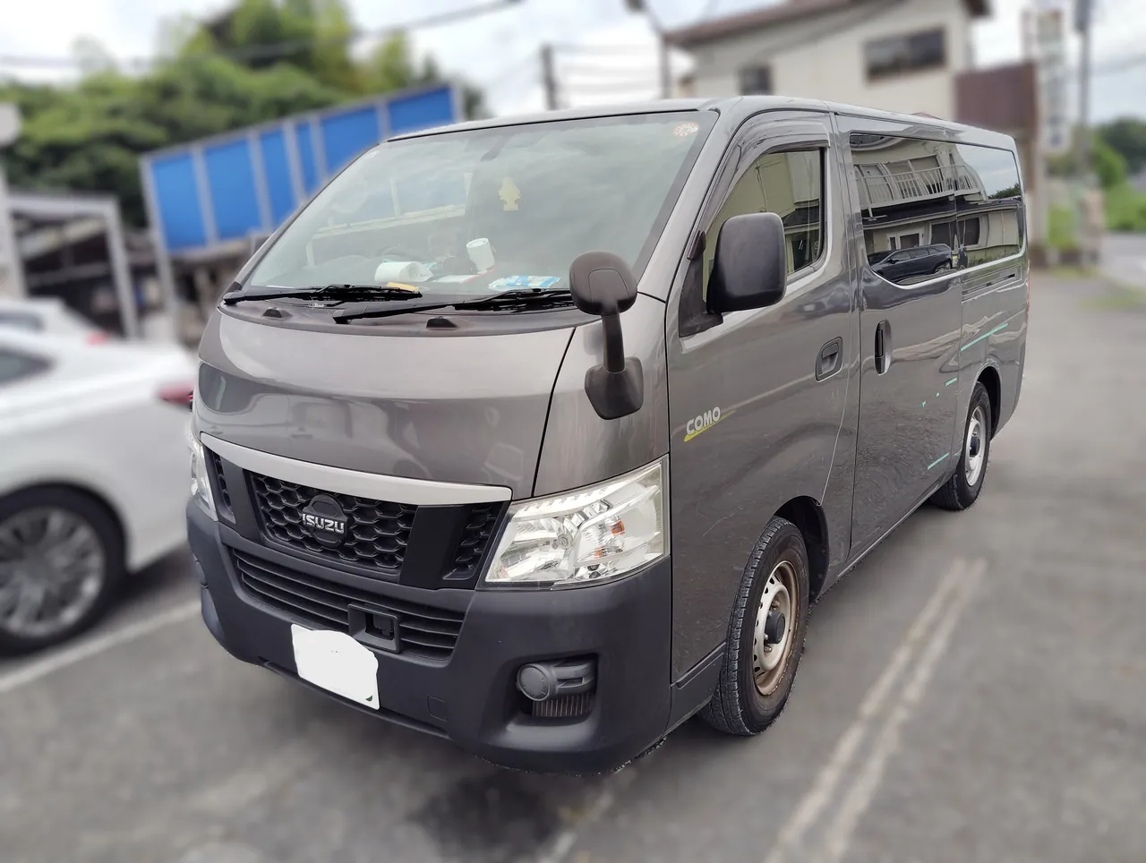 いすゞ・コモを前から。グリルにISUZUのエンブレム、左側面に損傷の目印の緑のテープ