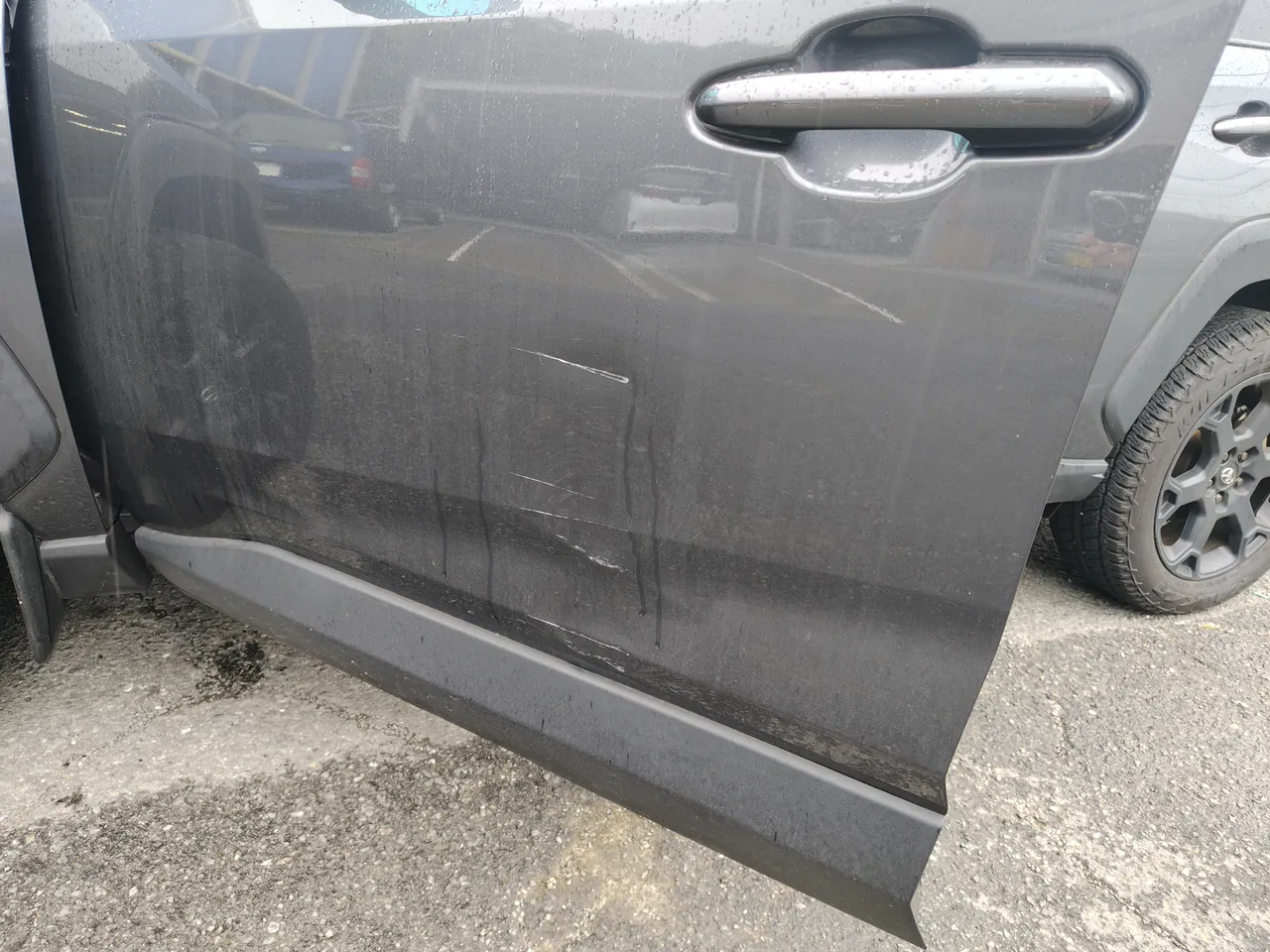 トヨタ RAV4 左フロントドアの下側の擦り傷。雨で濡れた車体