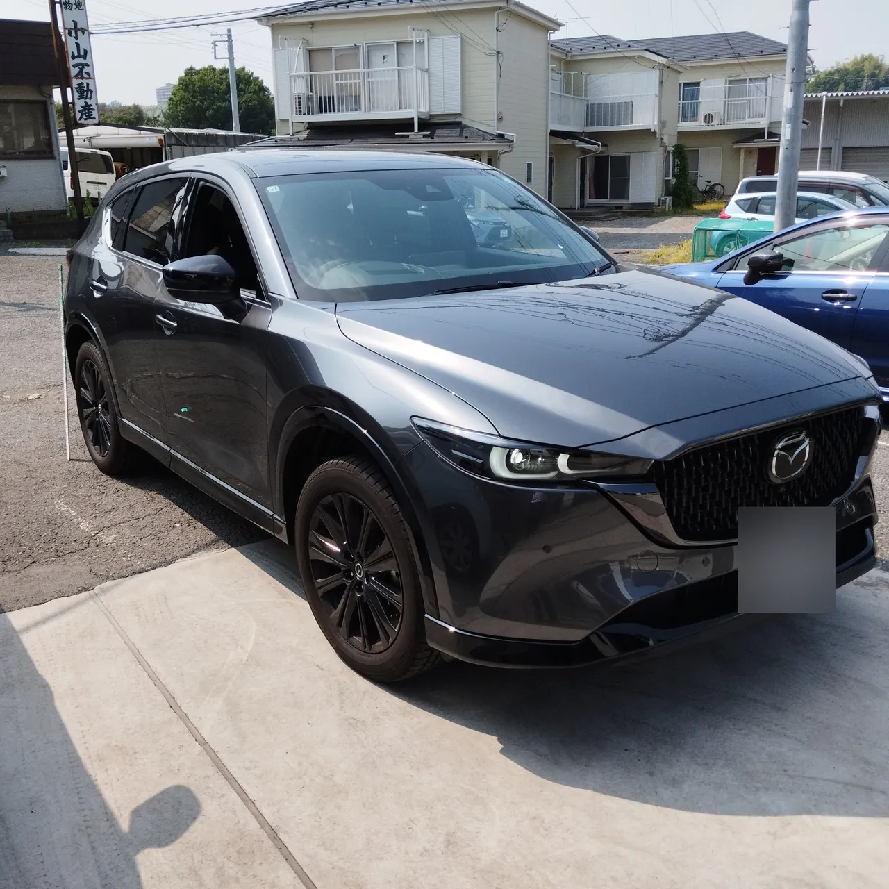 右前から見た修理前のマツダ CX-5。右フロントドアの下に緑のテープ