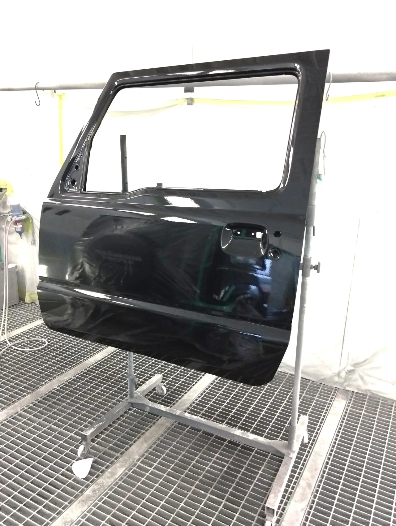 スタンドの上でZJ3を塗り終えた、ジムニーシエラの新しい左フロントドア。縁と内側の枠にもつや