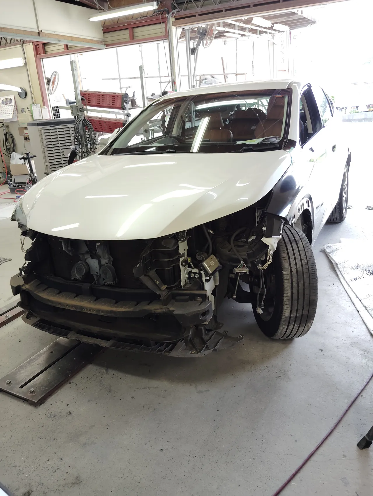 バンパーとヘッドライトを外したレクサスNXの正面。車の左に黒い新品のフェンダーが付いている