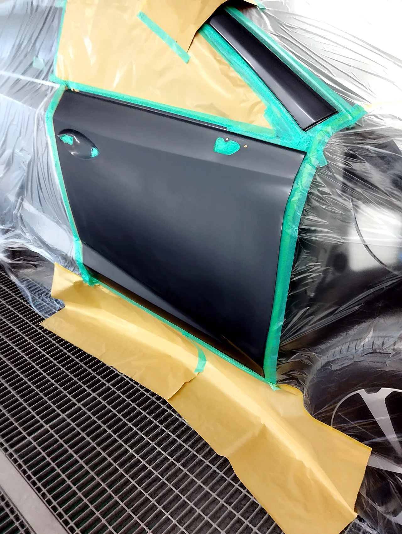 塗装ブースで、ドアのふちに沿ってマスキングした塗る前のレクサスNXの右フロントドア。ハンドルの穴はテープでふさぐ