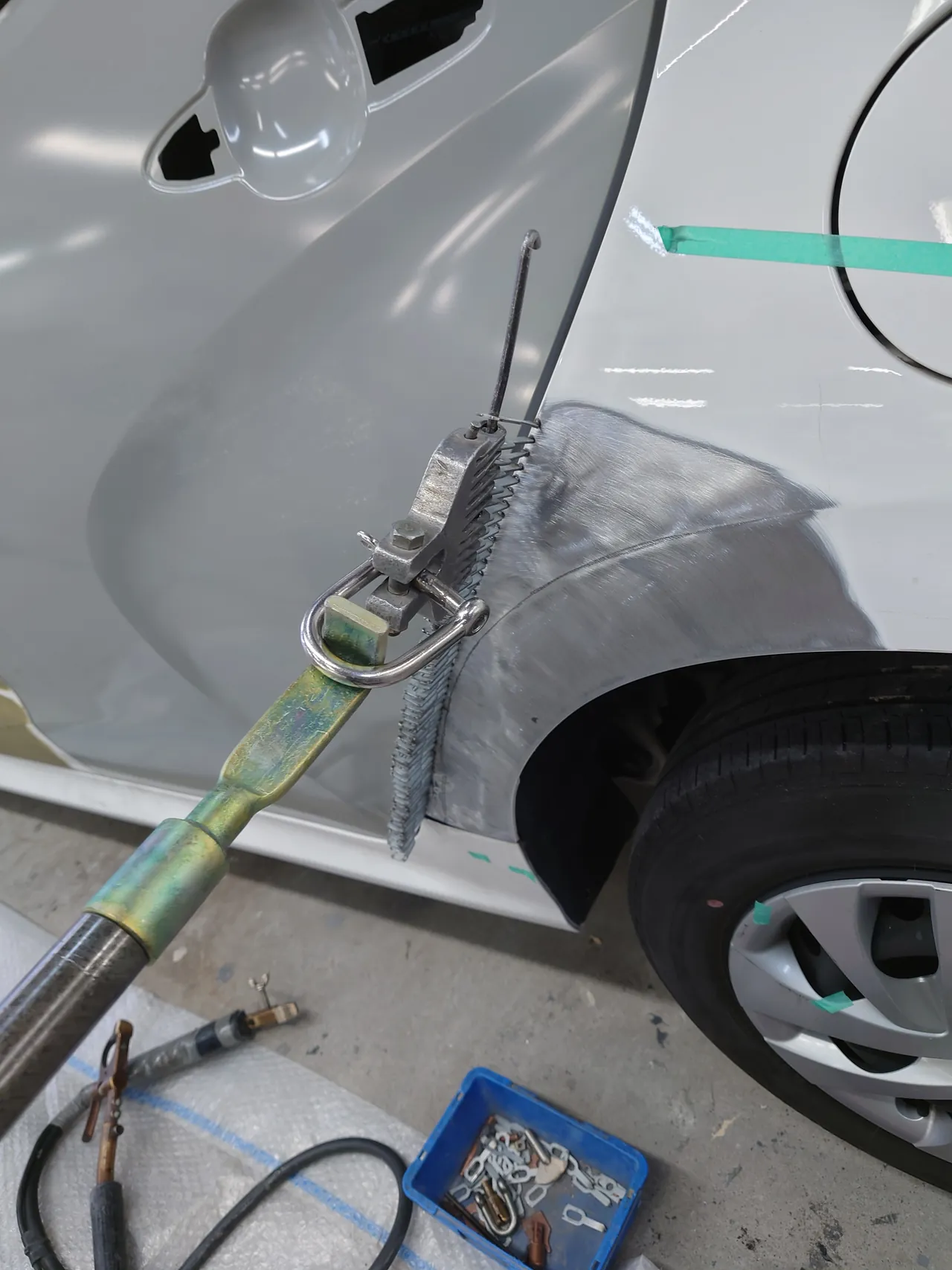 ヤリス ハイブリッドの左リヤクォーターの縁。溶接したワイヤーにフックを掛け、長い棒の工具で外へ引いている