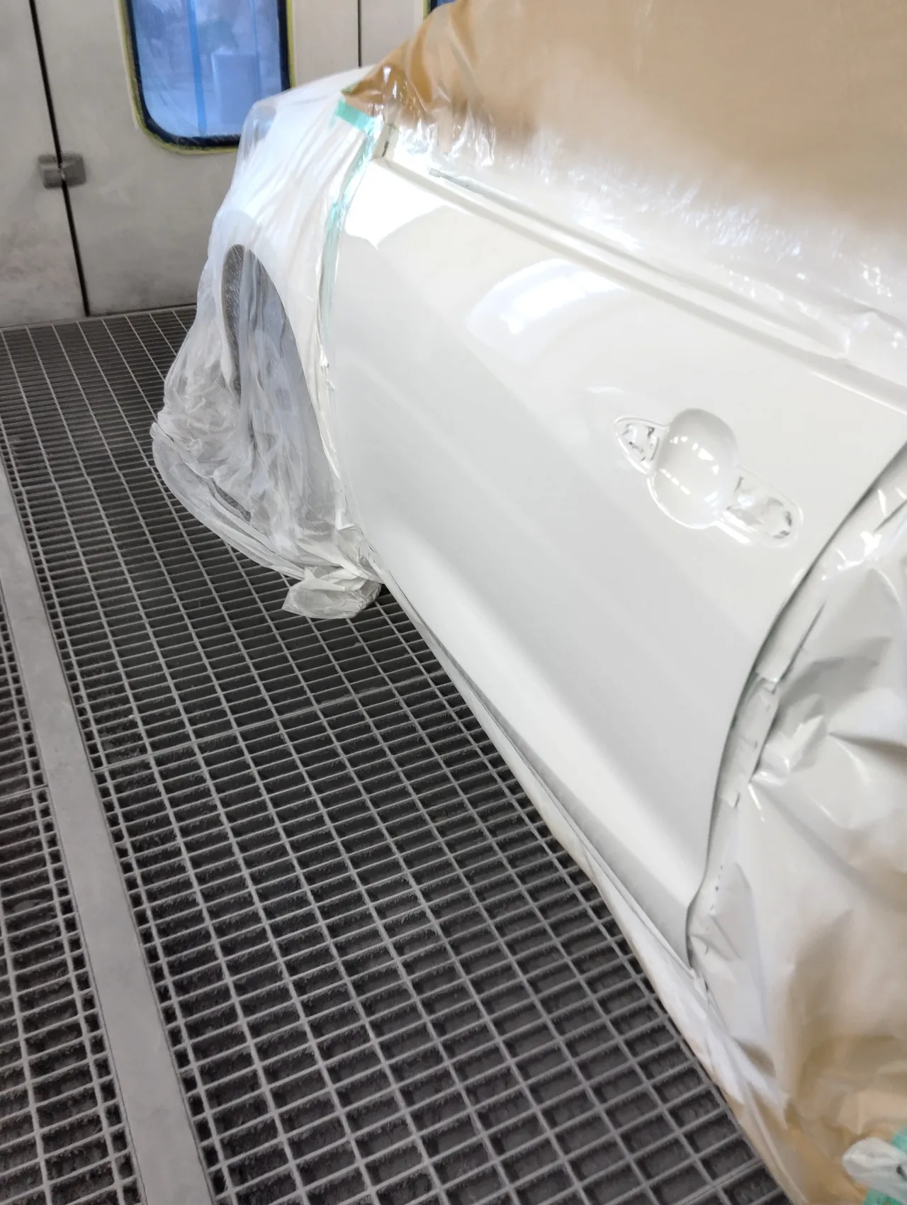 塗装ブースで040の白に塗り上げた、ヤリス ハイブリッドの左フロントドア（車に付けたまま）