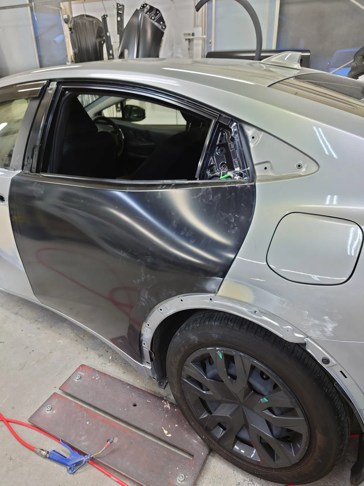色を付ける前の黒い新品の左リヤドアを車体に取り付けたプリウス(後ろ寄りから)。クォーターにはパテ