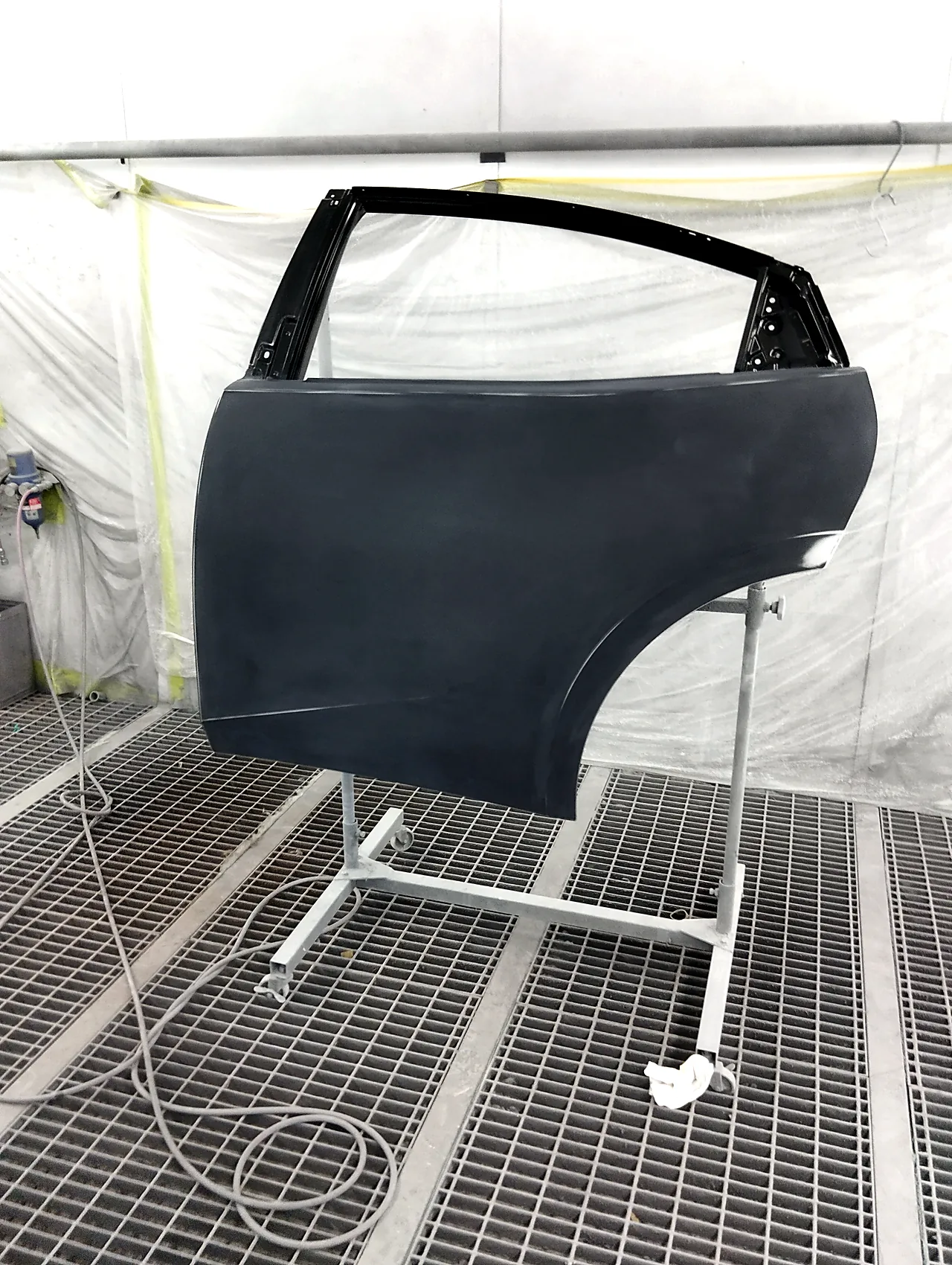 ブースの中でスタンドに載せた、まだ黒い新品のプリウス左リヤドア(塗る前)