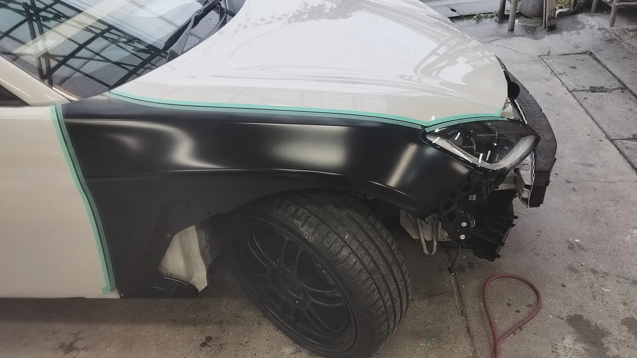色を付ける前の黒い新品の右フロントフェンダーをGR86の車体に取り付けた仮合わせ。ボンネットとドアとの境目に緑のテープ