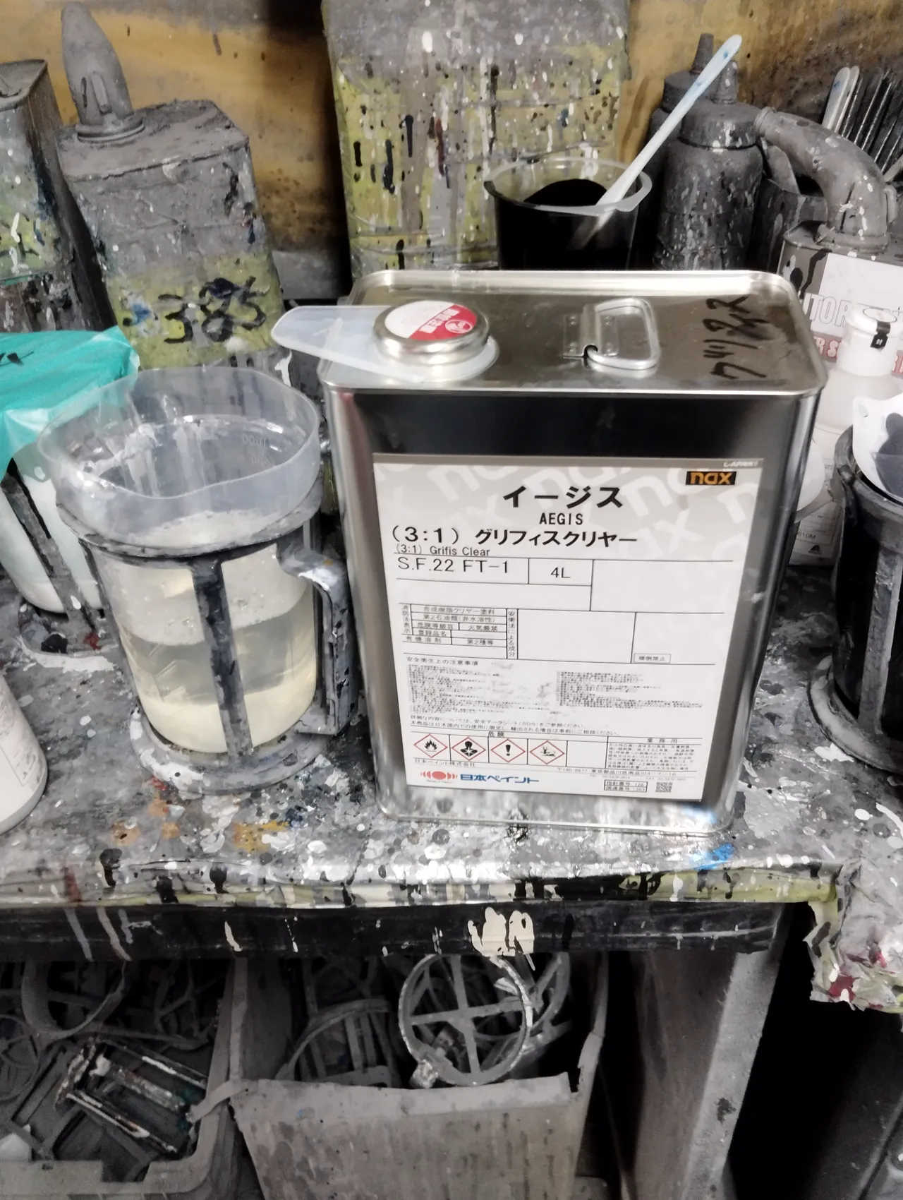 作業台に置かれたクリヤーの缶。40系アルファードの202の上に重ねた nax イージス(3:1)グリフィスクリヤー(日本ペイント)