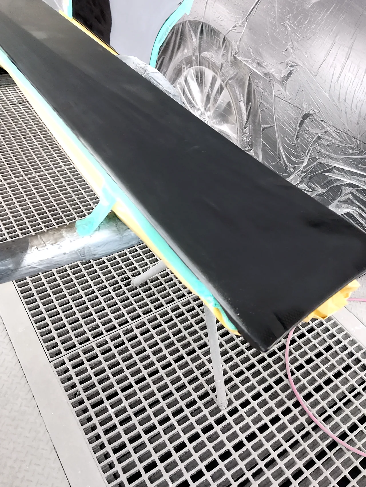 塗装ブースの台に載せた40系アルファードのスライドドアの下のガーニッシュ。表の面はつやのない黒