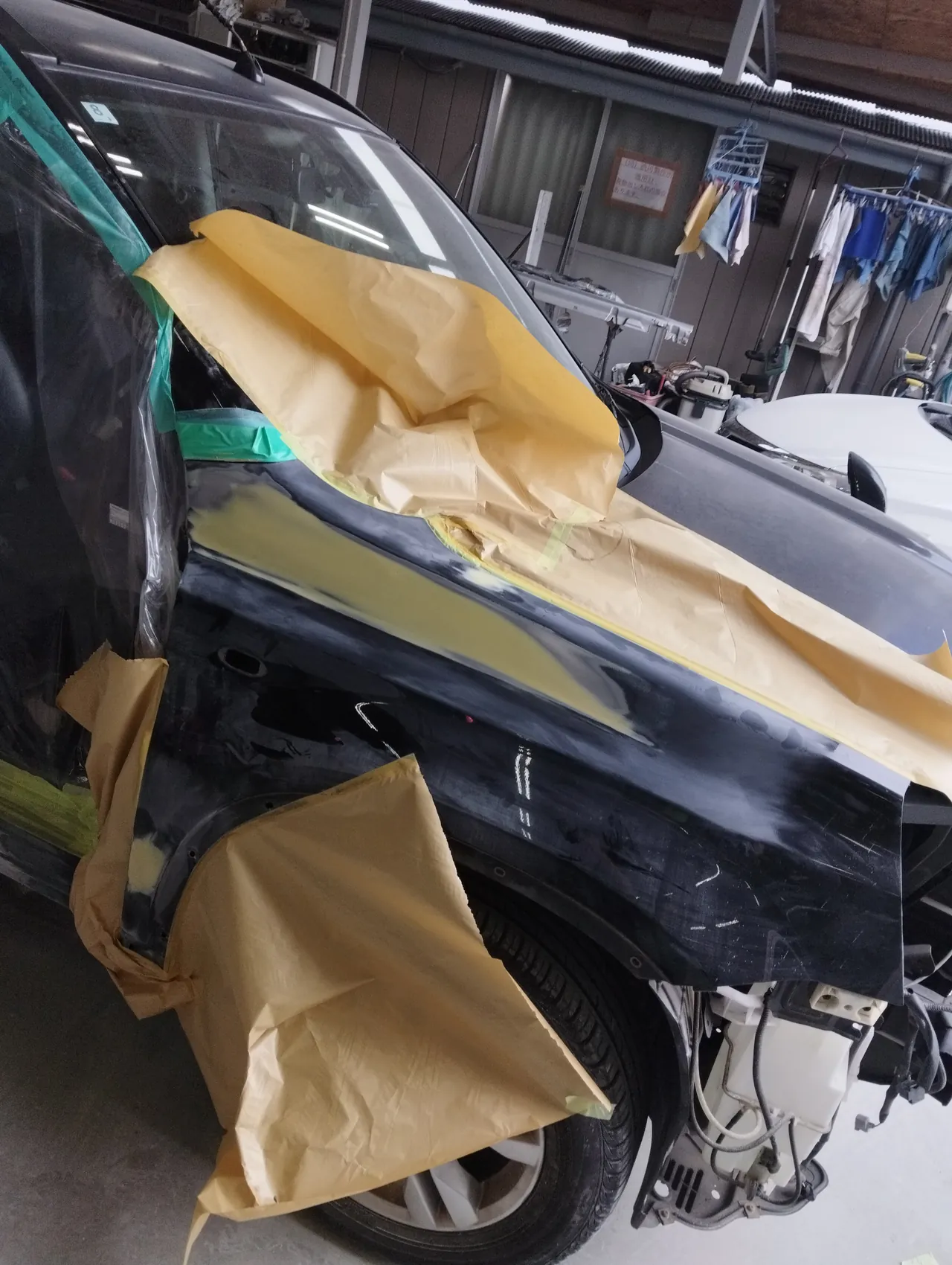 日産 T31エクストレイルの右フロントフェンダー。上の帯のパテを研ぎ、まわりを紙で囲んだところ(フロントバンパーは外してある)
