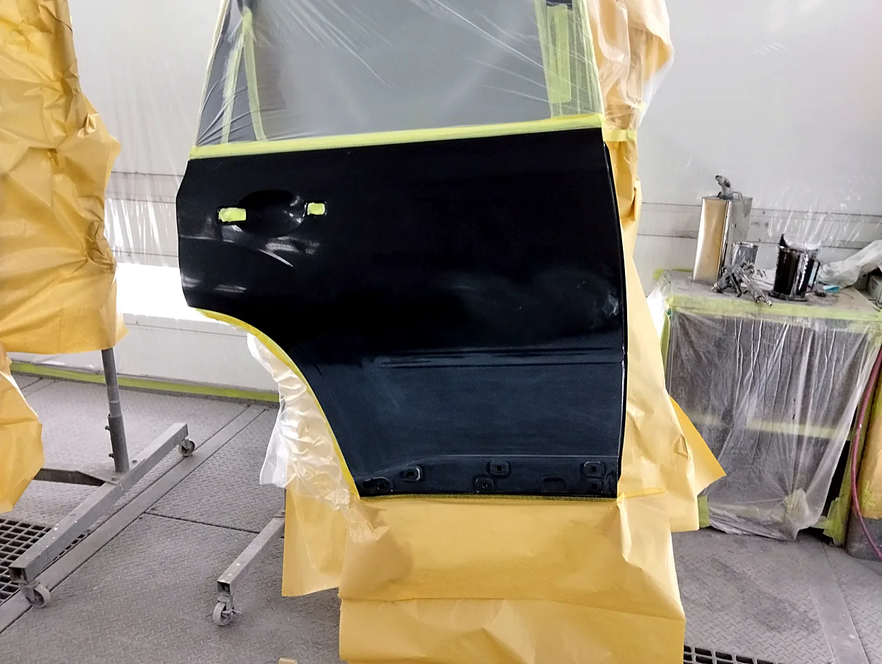 塗装ブースのスタンドに立てた日産 T31エクストレイルの右リヤドア(塗る前)。取っ手の穴にテープ