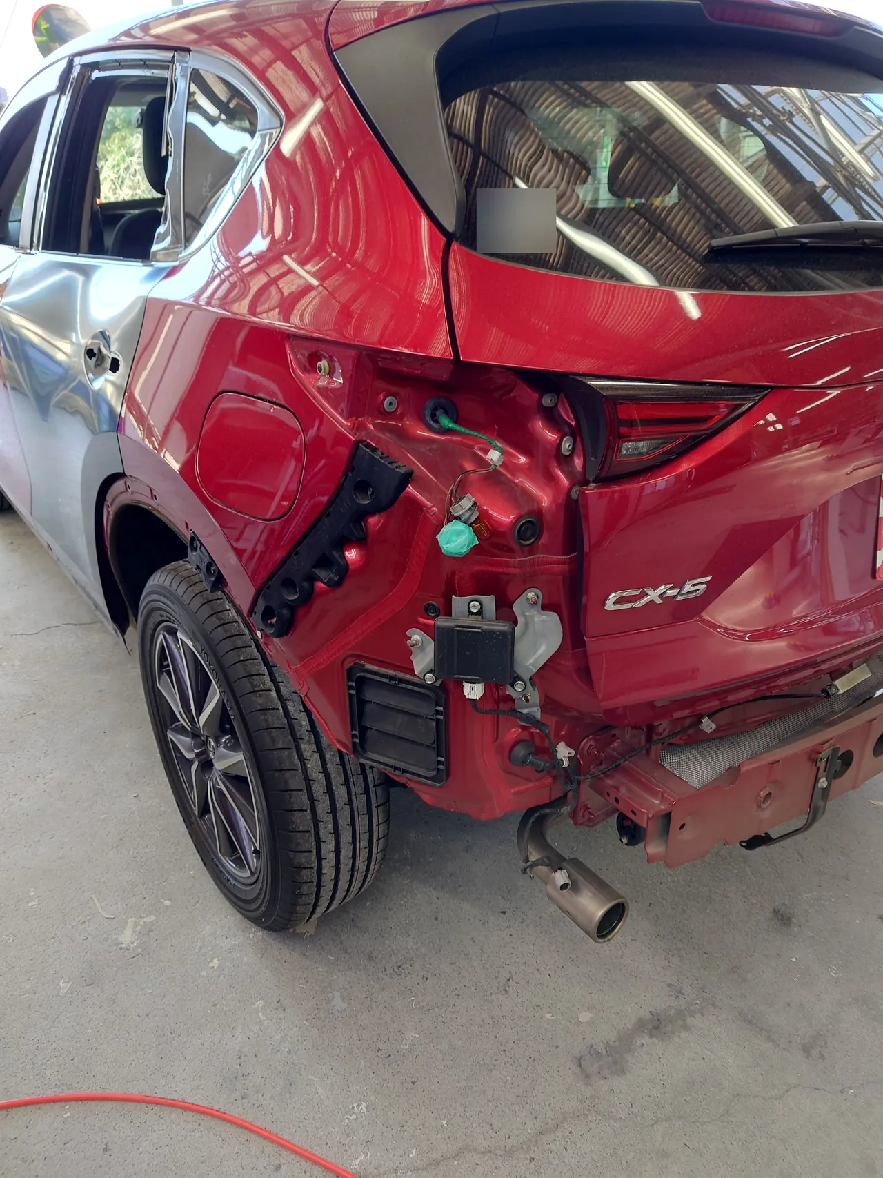 リヤバンパーを外したマツダ CX-5の左後ろ。左リヤドアは新しいドアに替わっている