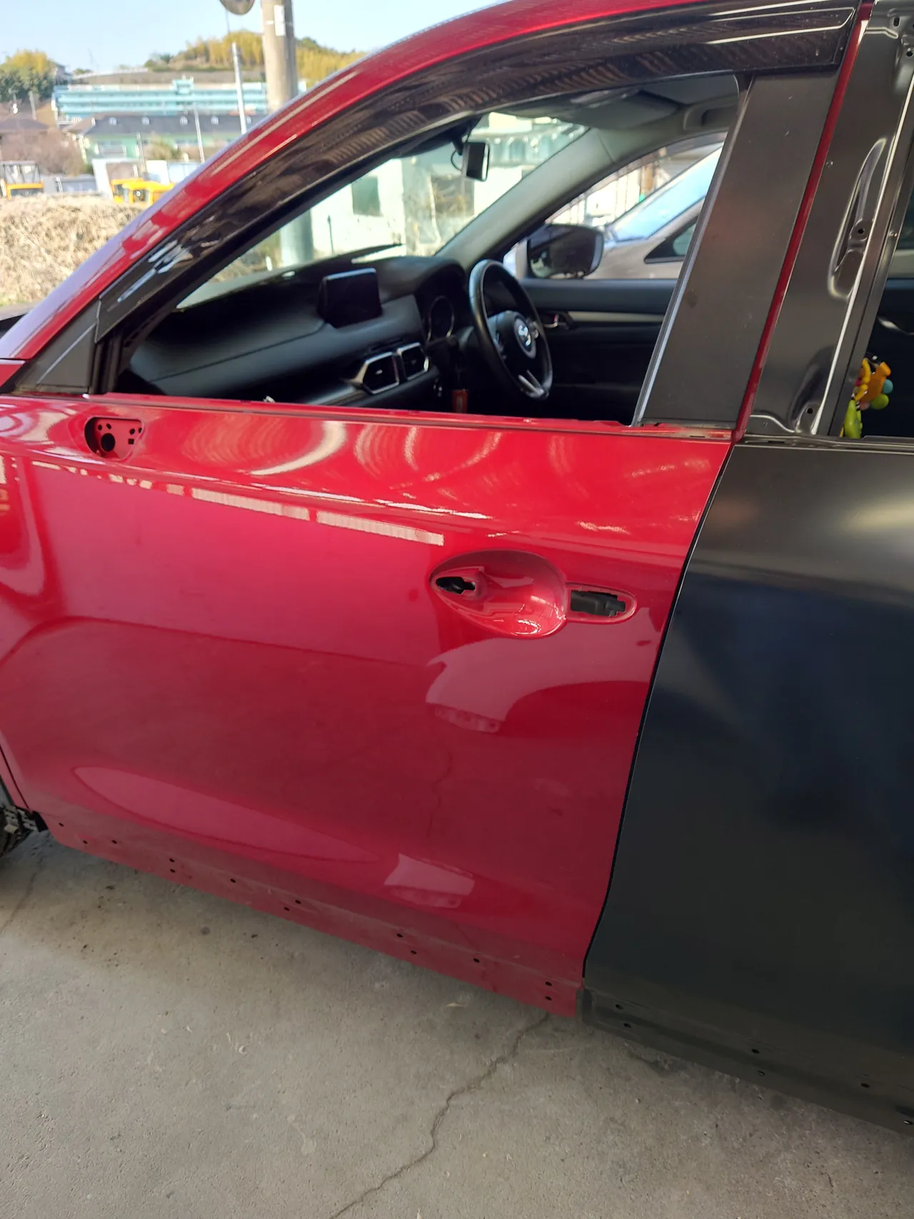 外側のハンドルを外したマツダ CX-5の左前ドア。右に仮付けした黒い新しい左リヤドア