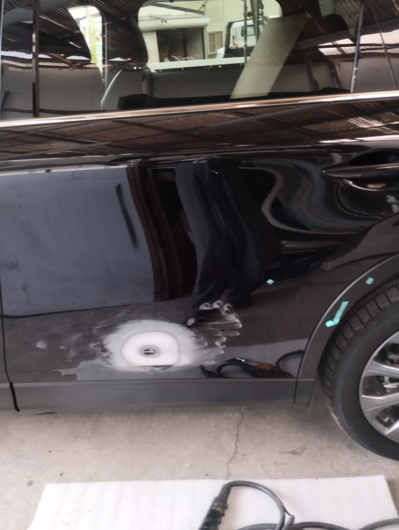 CX-80の左リヤドア下。へこみのまわりの塗装を研いで、白い研ぎ粉が輪の形に残る