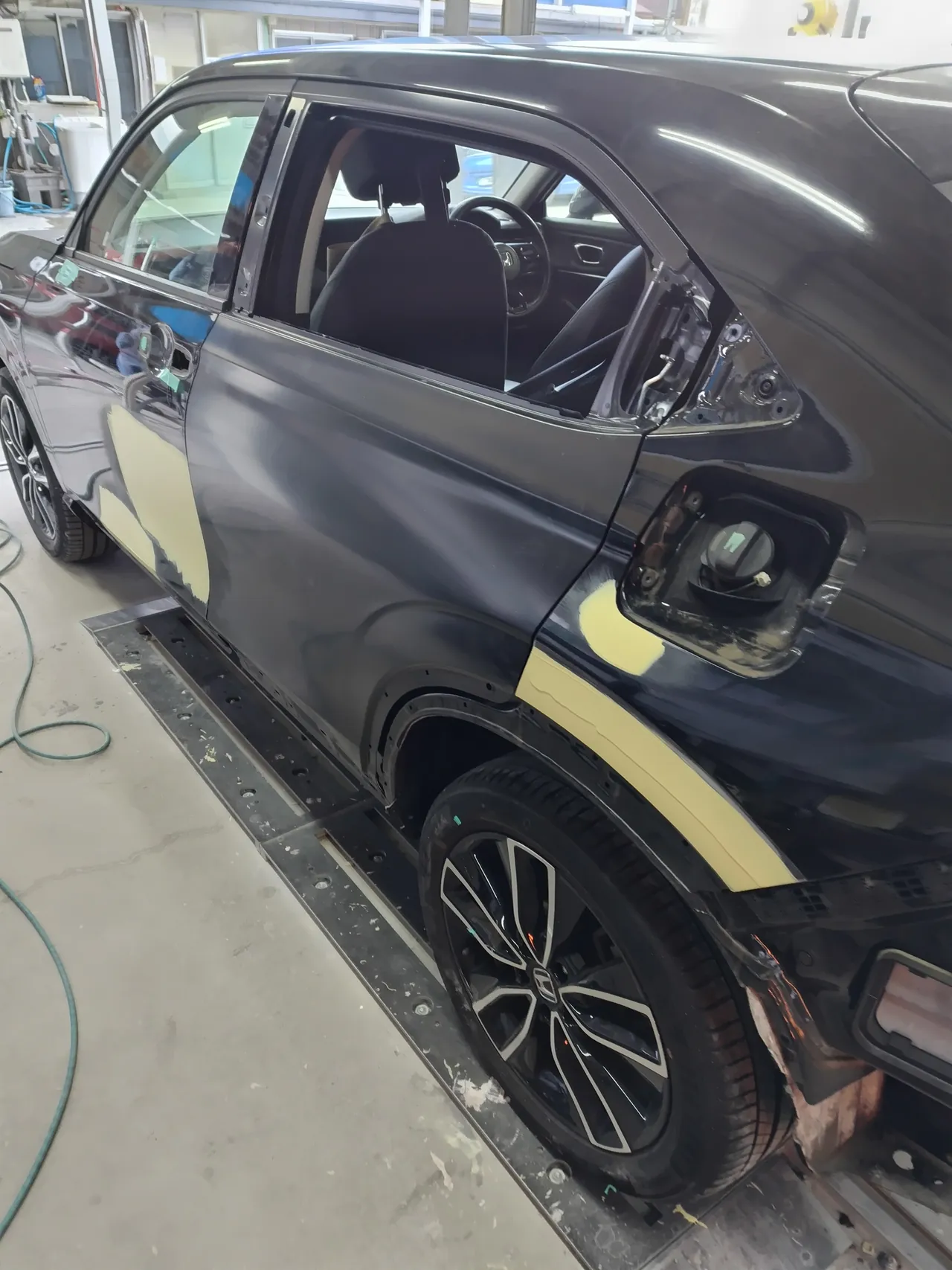 ヴェゼル e:HEVの左側面。取り寄せた左リヤドアが塗る前のつやの少ない黒のまま車体に付き、前ドアと左リヤクオーターに淡い黄色のパテ