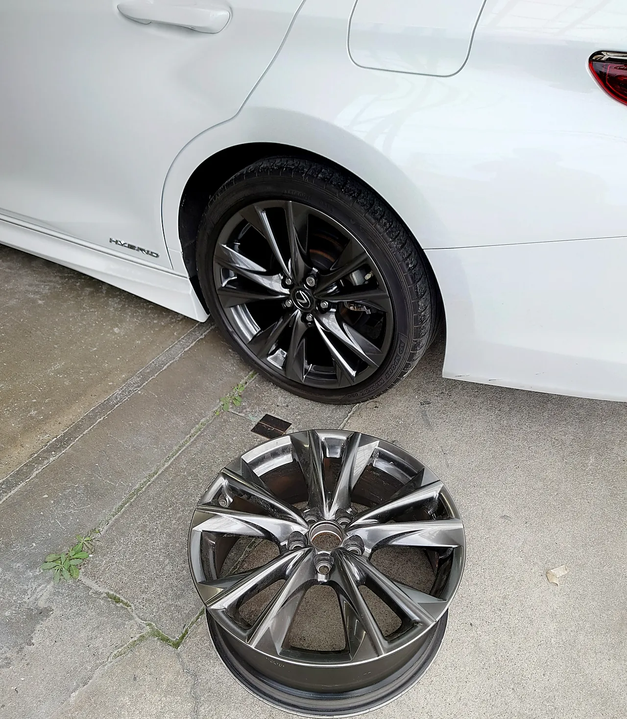 修理を終えたレクサスESの左後ろの車輪と、床に置いたタイヤの付いていないホイール