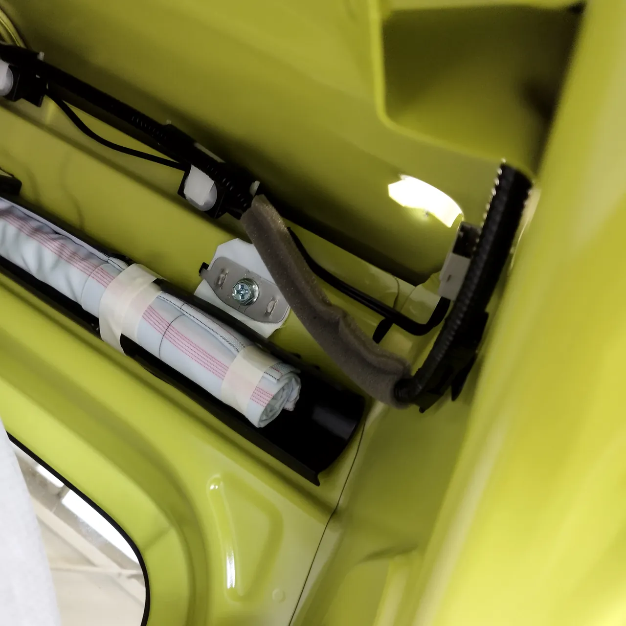 ジムニー（JB64）の屋根の横のふちの内側。テープで束ねた細長い部品と配線が通る