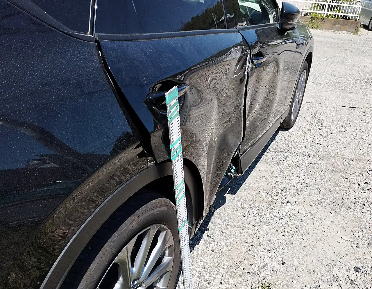 CX-60の右リヤドアの後ろ寄り。外側のハンドルのまわりから映り込みがゆがむ所に目盛りの棒(修理前)