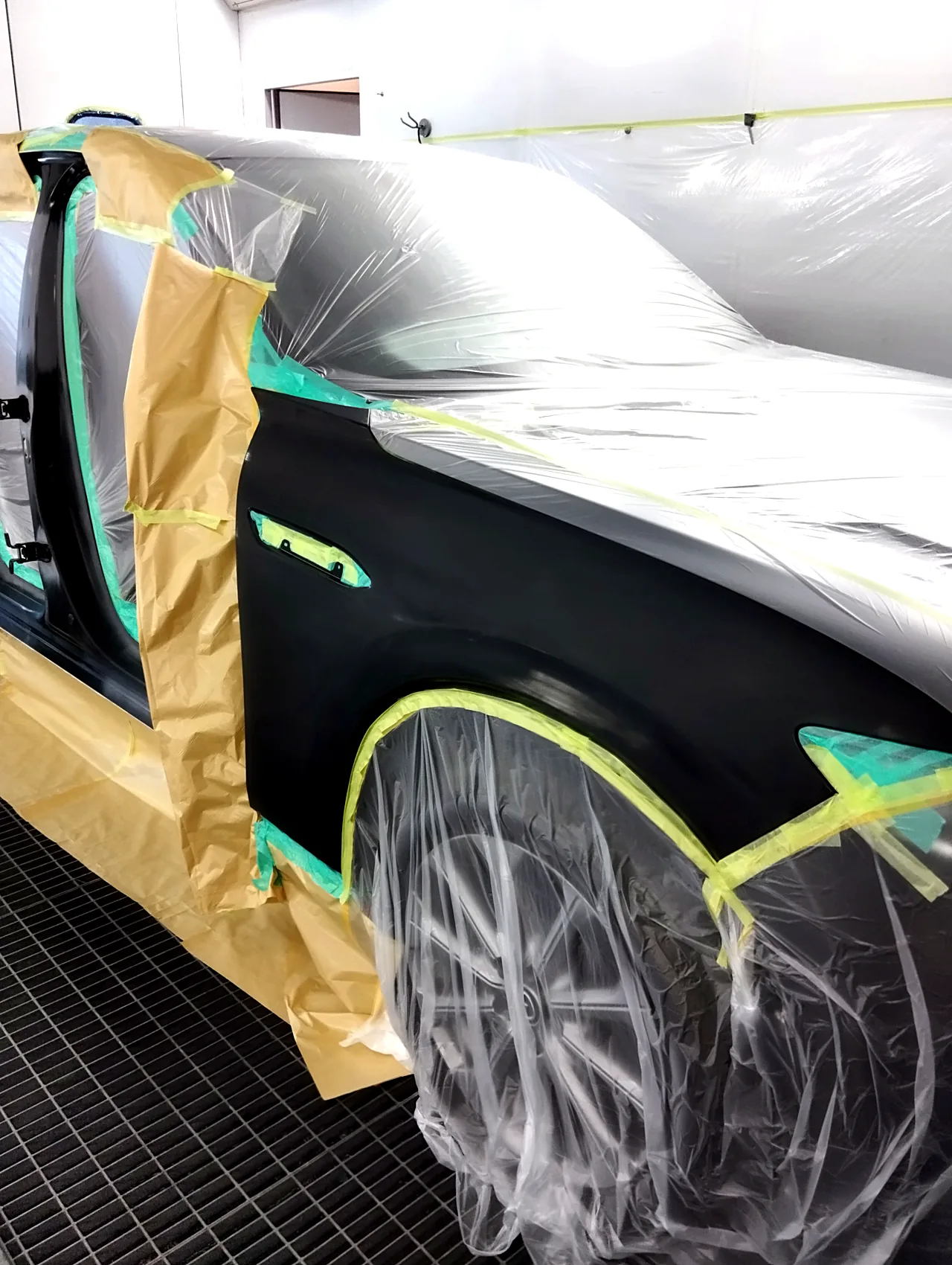 塗る前のマツダ CX-60の右前フェンダー。つやを研ぎ落とし、ドアの開口部は紙、ボンネットとタイヤにはビニールをかぶせる(塗装ブースの中)