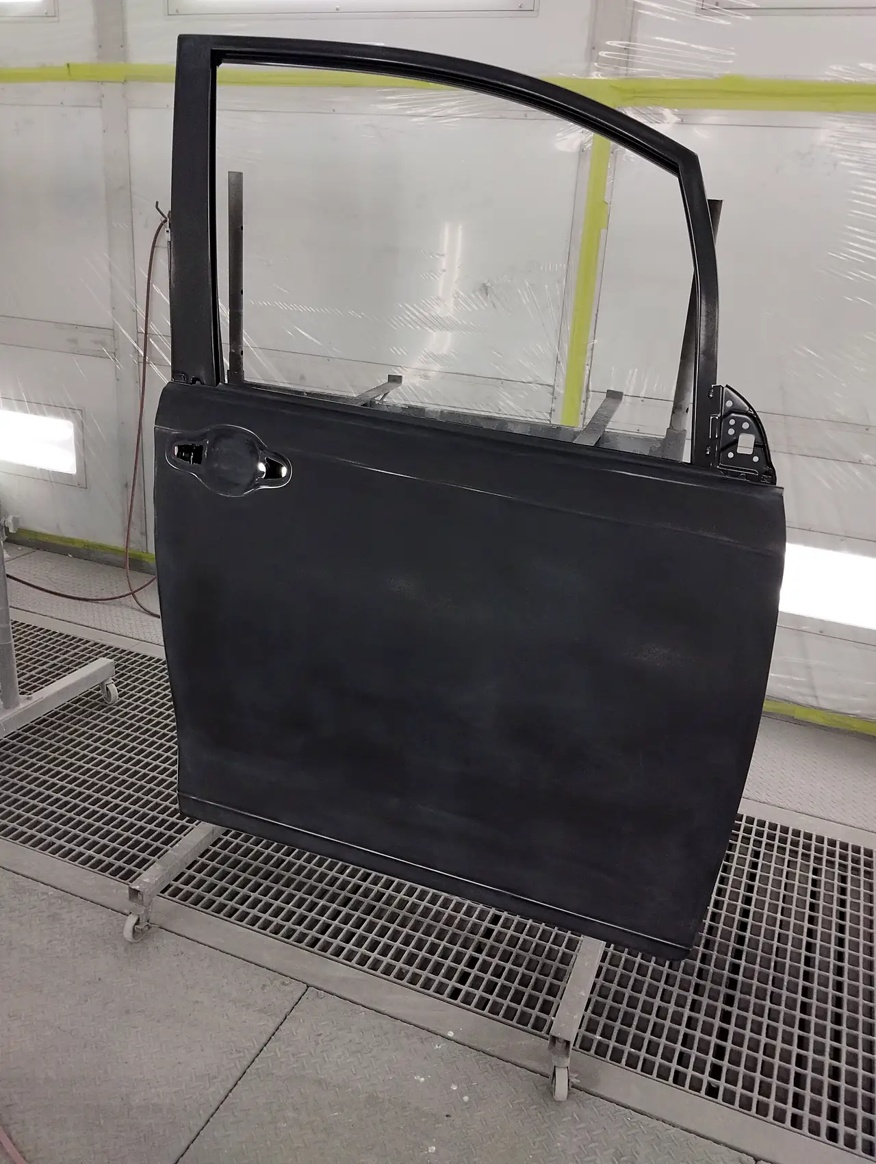 塗装ブースのスタンドに立てた、エスクァイアの取り寄せた右前ドア。車の色を塗る前の下地の状態