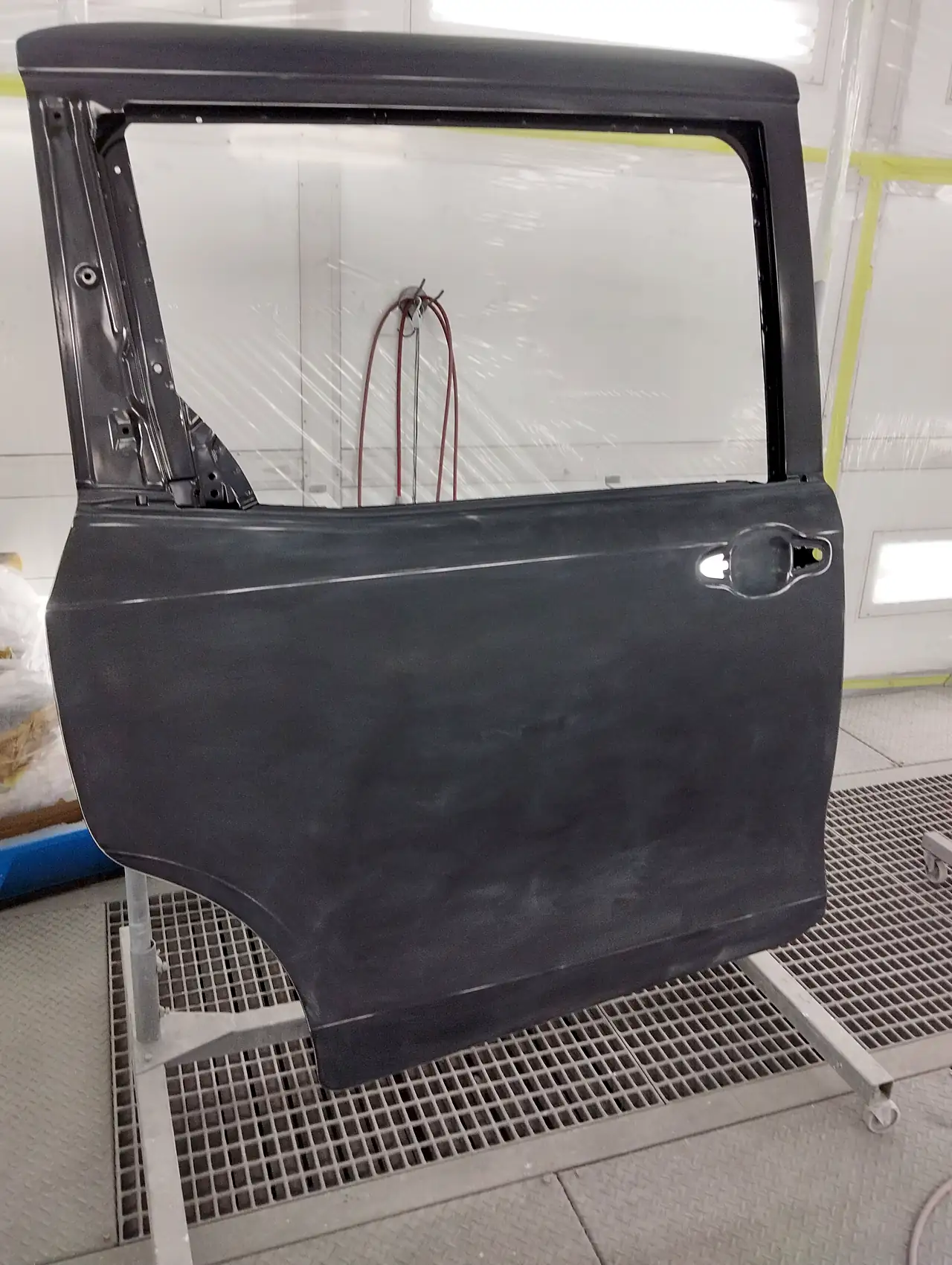塗装ブースのスタンドに立てた、エスクァイアの取り寄せた右スライドドア。車の色を塗る前の下地の状態