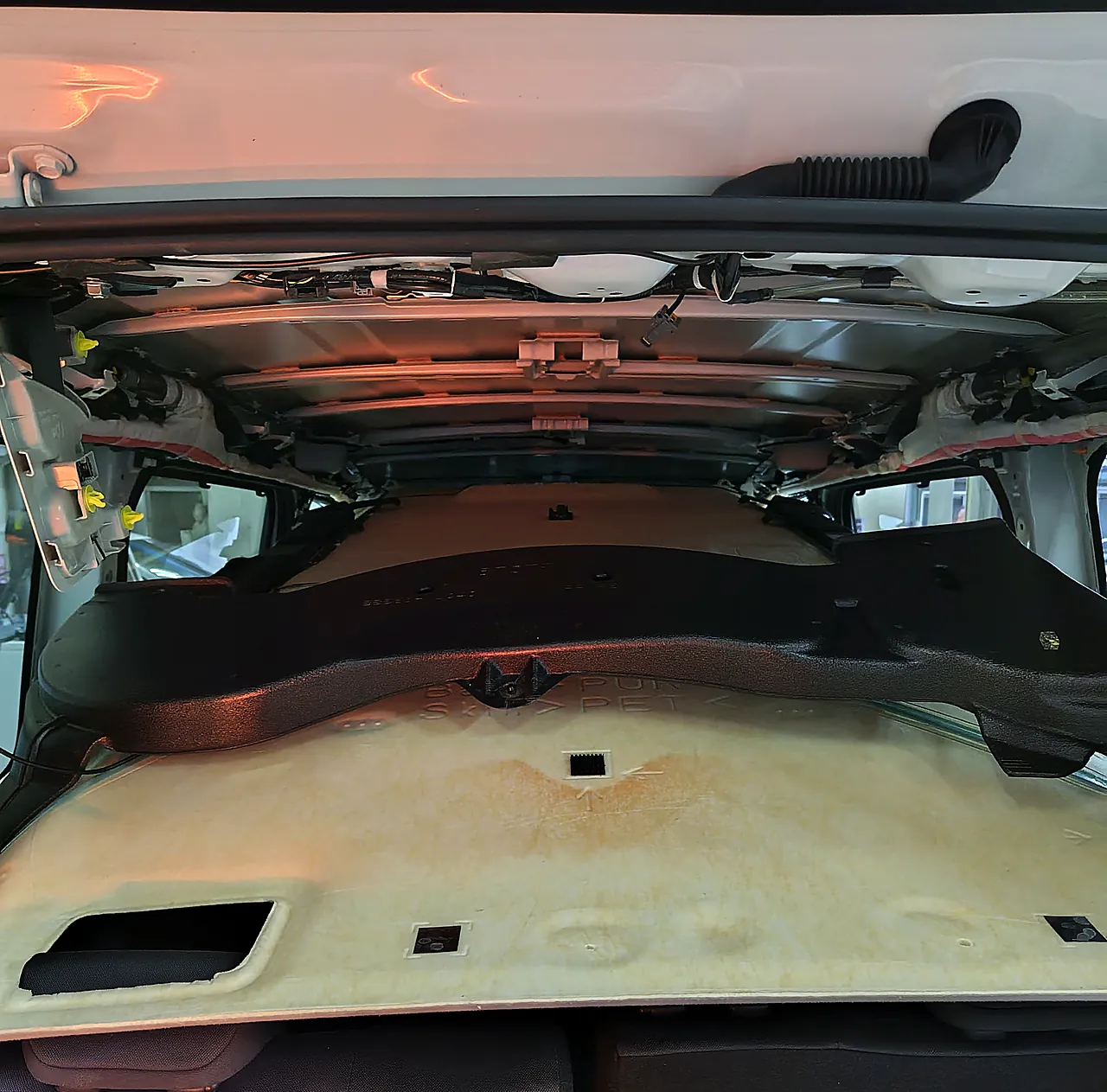 バックドアの側から見た90系ノアの車内。天井の内張りの後ろ寄りを下ろし、奥に屋根の裏の鉄板と梁が見える
