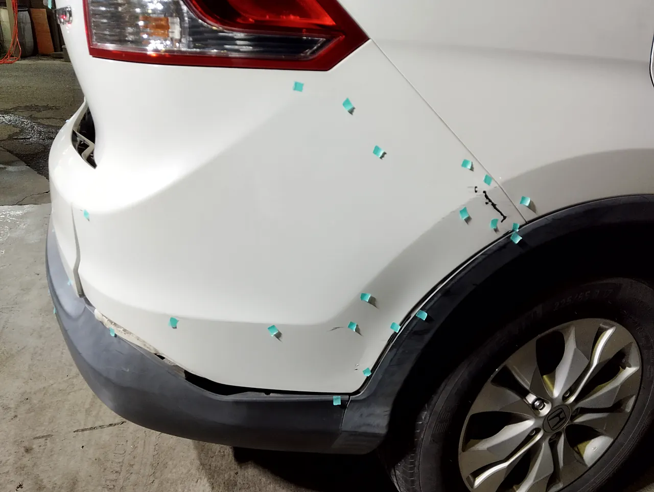 修理前のホンダ CR-V の右の後ろの角。バンパーの角が外れ、リヤクォーターにも傷（緑のテープの印）