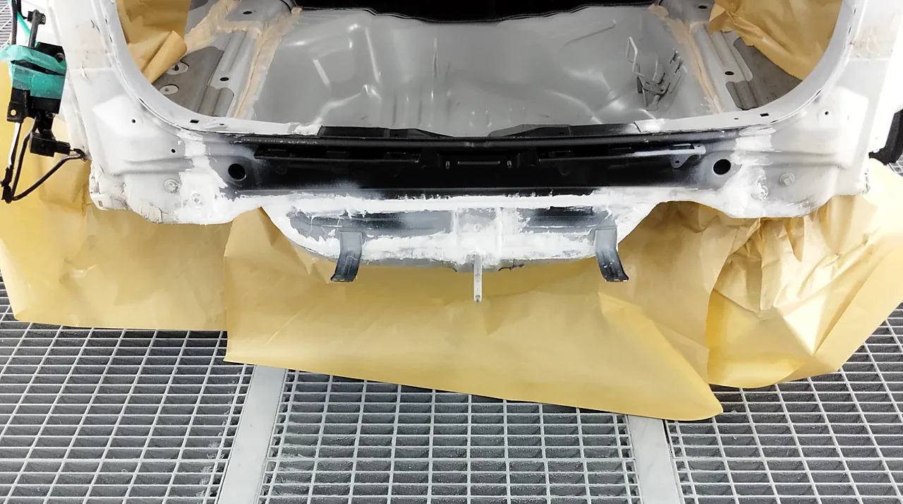 塗装ブースのホンダ CR-V の後ろの端。まわりを紙でマスキングし、新しいバックパネルの下に白いシーラー（塗る前）