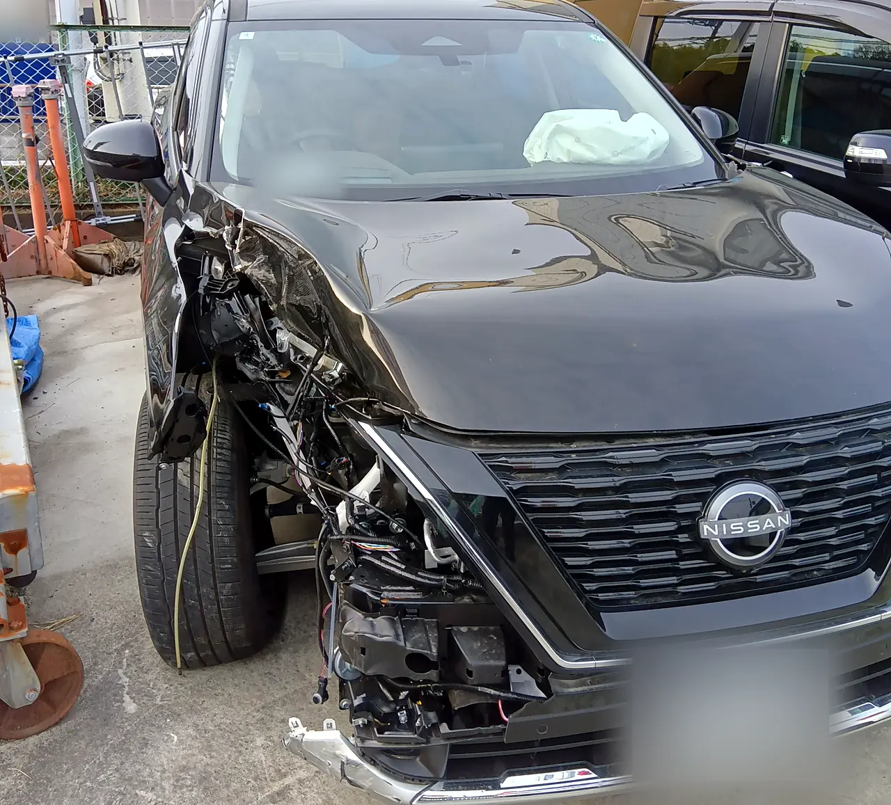 修理前のエクストレイル(T33)を正面のやや右から。右ヘッドランプがなく、ボンネットの右前がつぶれ、ガラス越しに開いた助手席のエアバッグ