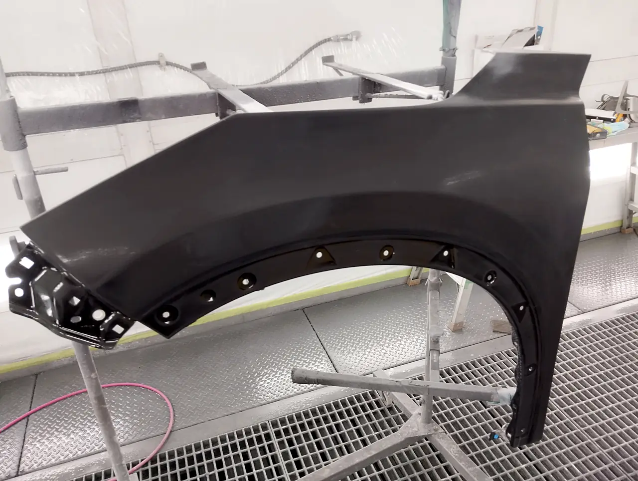 塗装ブースのスタンドに立てたエクストレイルの左フェンダー。表面を研いでつやを消した状態(足付け)