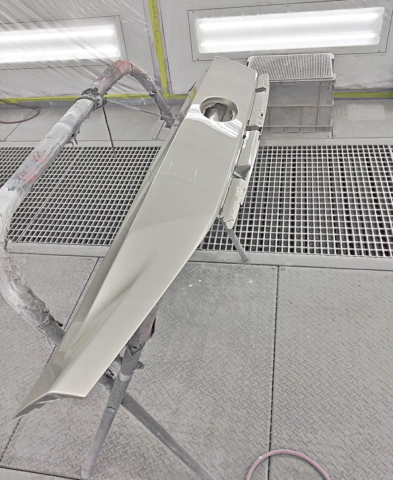 塗装ブースの台の上で、4X8に塗り終えたレクサスRXのバックドア上部パネル。エンブレムの穴と、照明の映り込み(塗装後)
