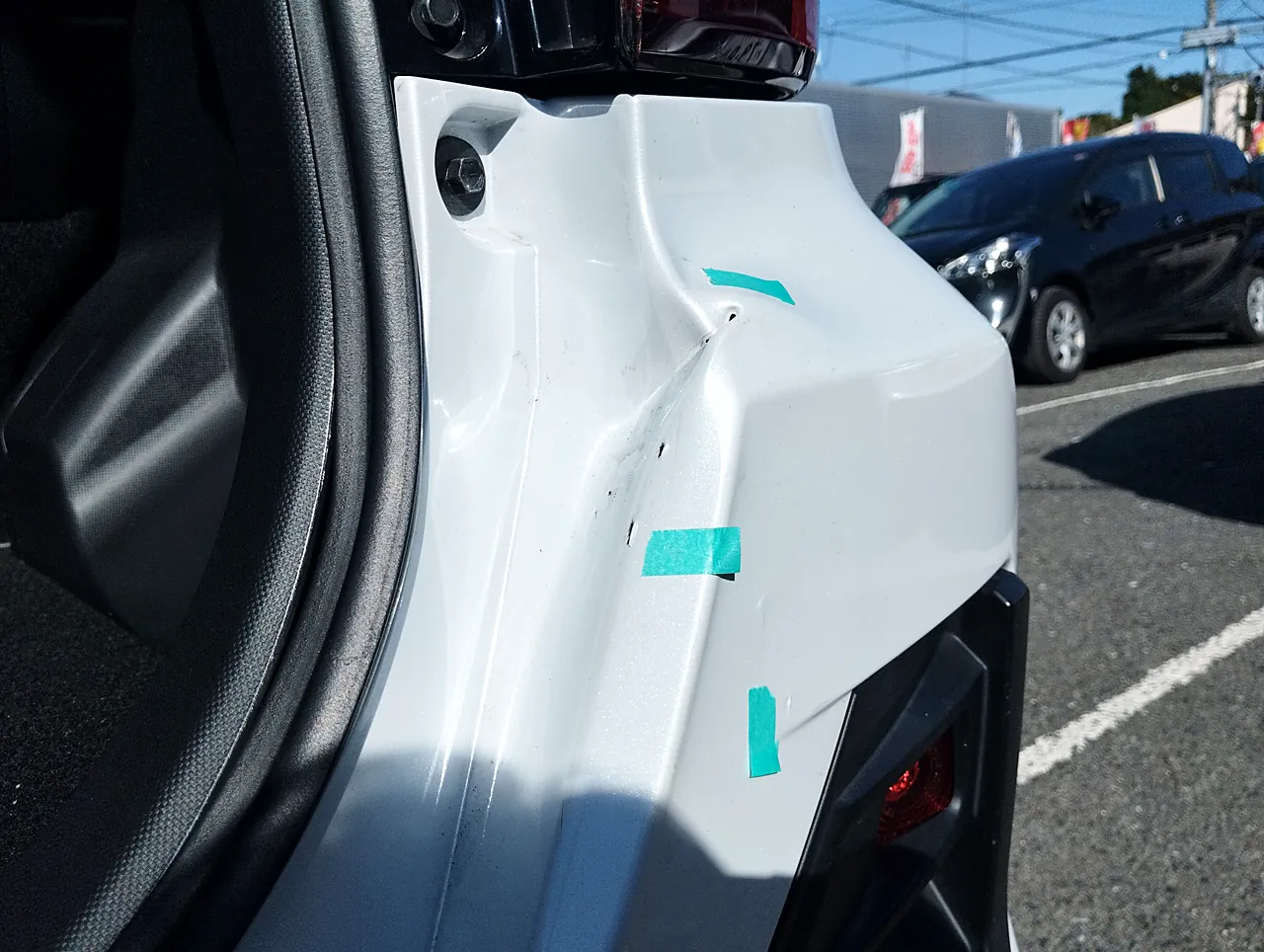 バックドアを開けたライズの開口部の右の縁。鋭い線の入ったへこみと緑のテープの印(修理前)