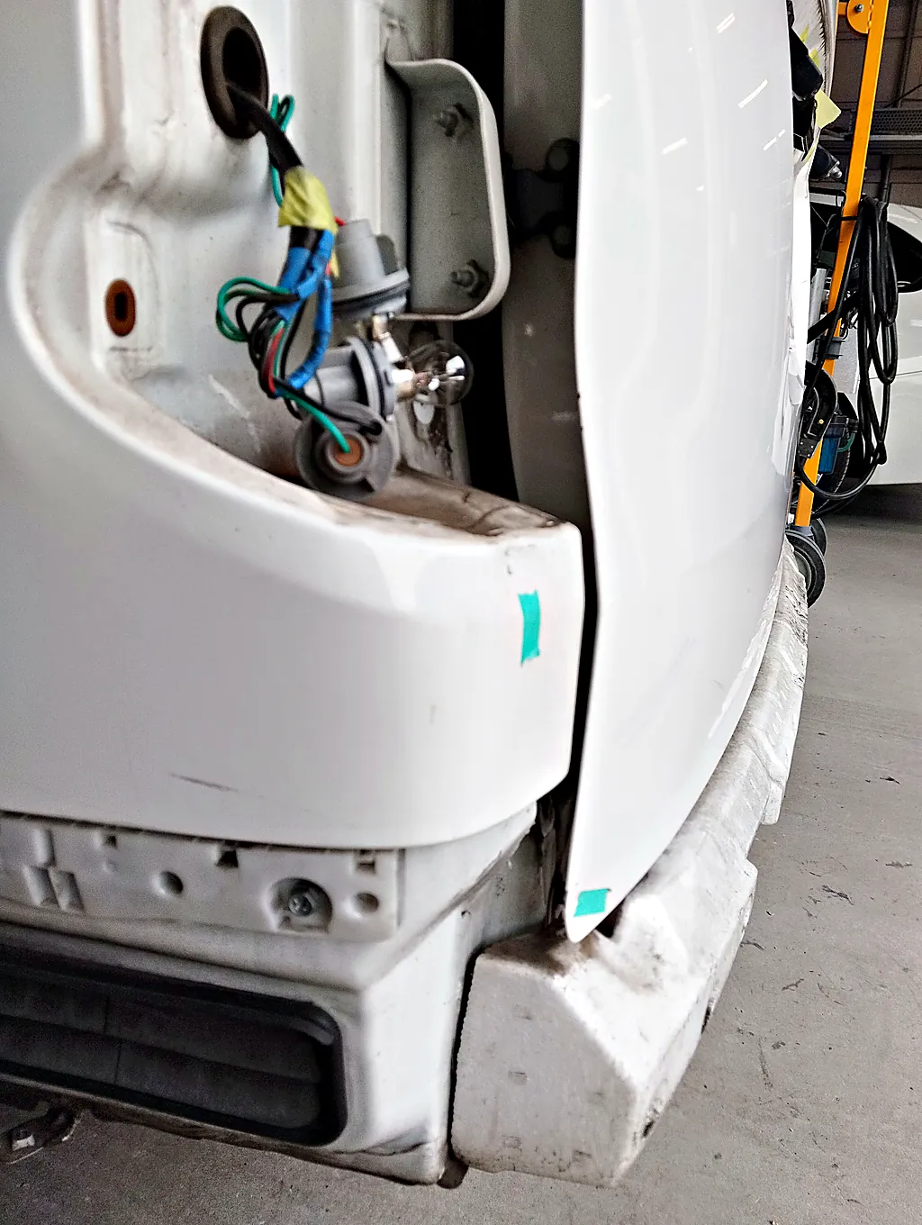 リヤバンパーと左テールランプを外したNV200バネット バンの左後ろの角。ランプの配線と、バンパーの取付け部が見える