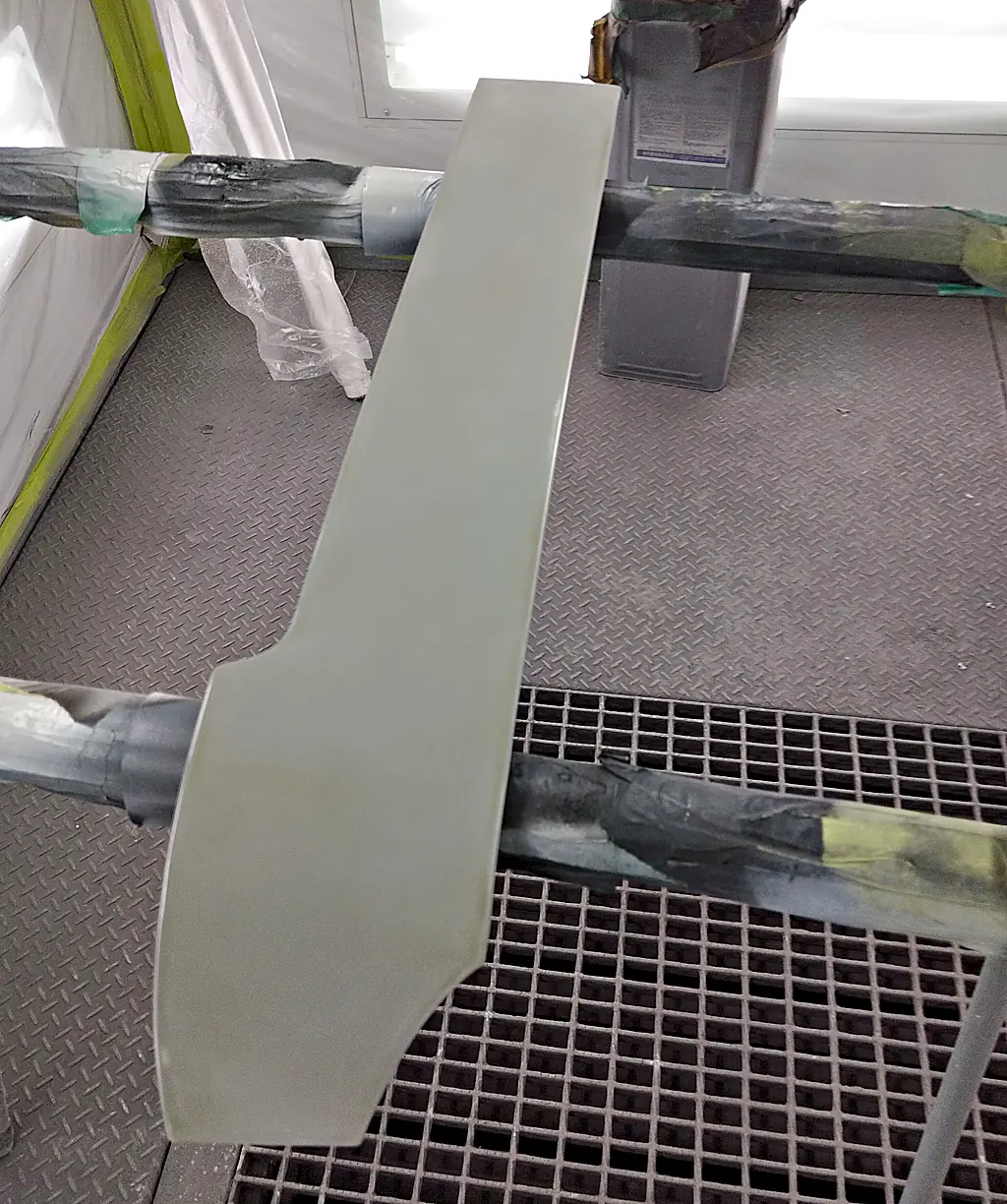 塗装ブースのスタンドに載せた、ソリオのクォーターに付く細長いカバー(まだ車の色が塗られていない状態)