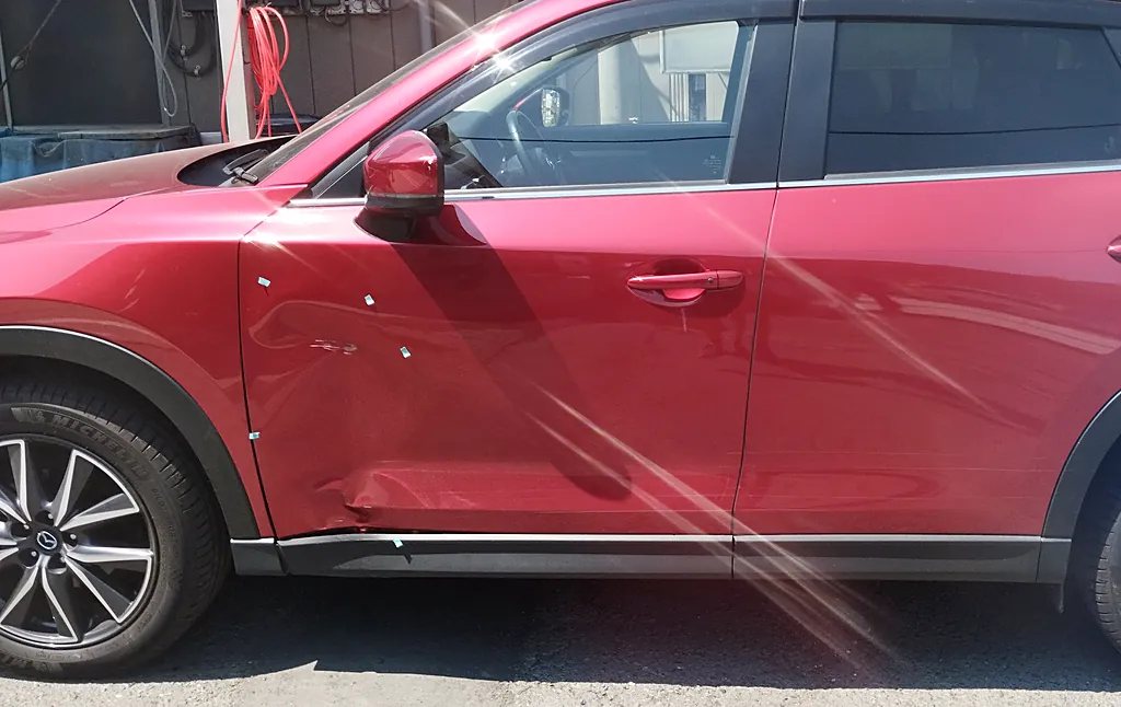 修理前のCX-5の左側面を横から。前ドアの下の前寄りのへこみと目印のテープ