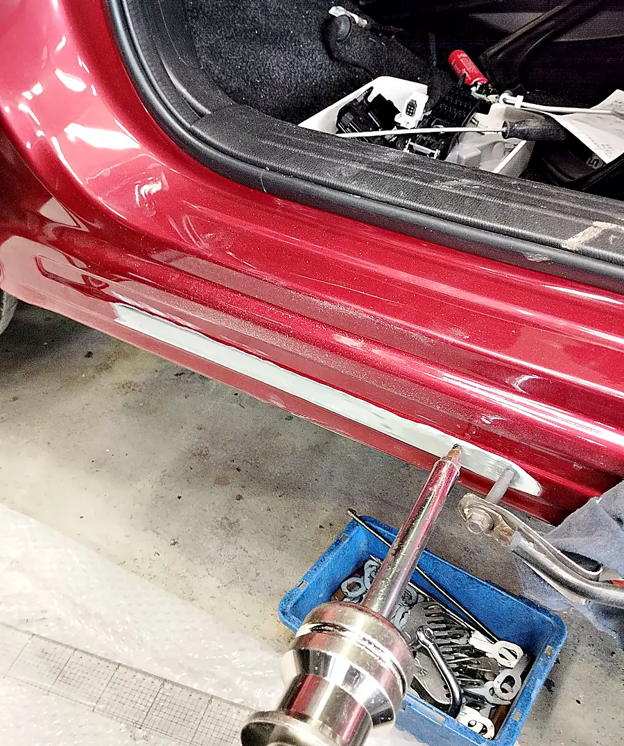 CX-5の左サイドシルの下の端に、溶接式の引き出し工具（スライドハンマー）の先を当てたところ