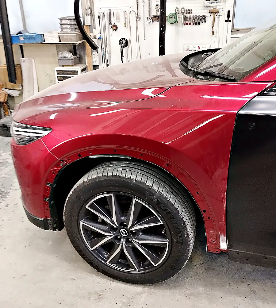 ホイールアーチのモールを外したCX-5の左フロントフェンダーと、右に仮付けした新しい前ドア（まだ車の色が塗られていない状態）