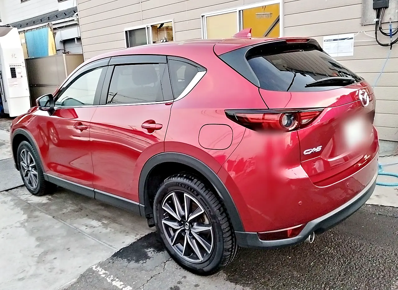 修理を終えたCX-5を左後ろの斜めから。前ドアから左リヤドアまで続く赤（外で撮影）