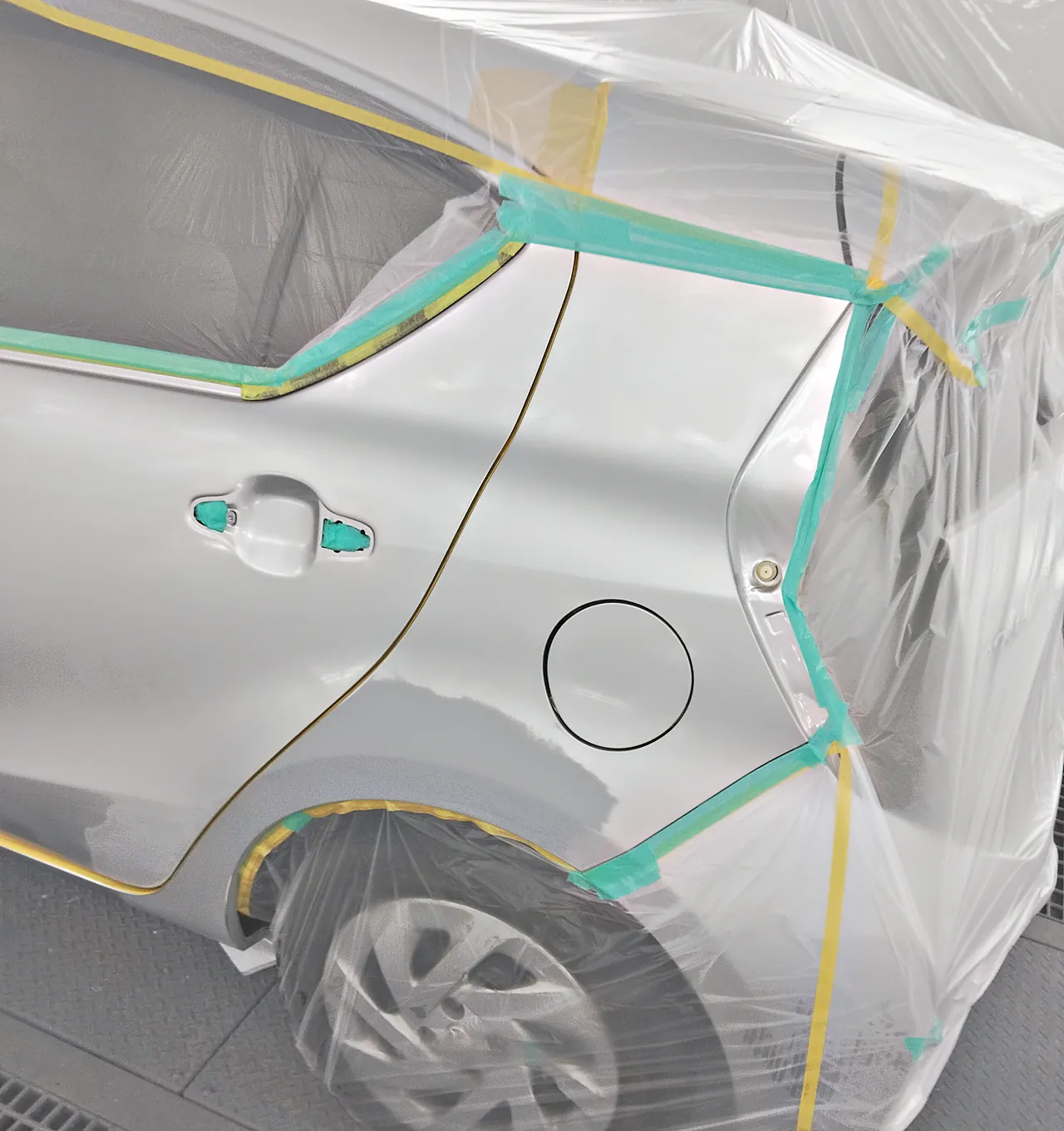 塗装ブースの初代アクア。車全体をビニールで包み、左リヤドアと左リヤクォーターだけを出してテープで区切ったところ(左後ろ寄りから・塗る前)