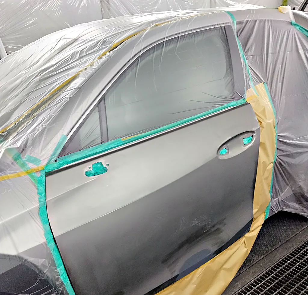 レクサスUX250hの左前ドア。ふちと取っ手の穴をテープでふさぎ、後ろのふちから足もとを紙で覆ったところ（塗装ブース・塗る前）