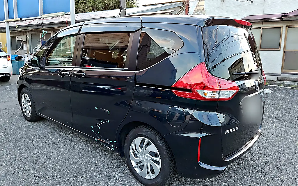 お預かりしたホンダ フリード（2代目）を左後ろの斜めから。スライドドアの後ろの下とサイドシルに緑のテープと擦り傷（修理前）