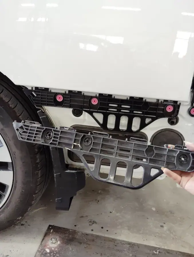 塗装を終えた車体の左後ろに、バンパーを支える部品を取り付けているところ