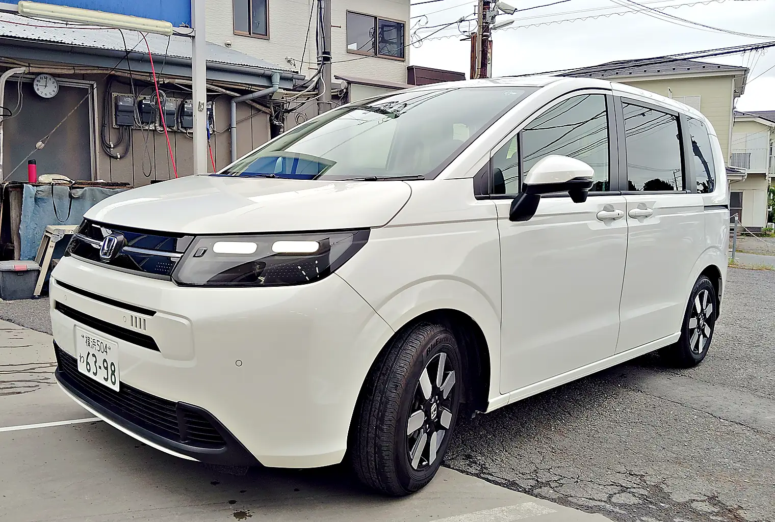 パールホワイトのフリード e:HEV の左斜め前。黒い部分のある2色のアルミホイール
