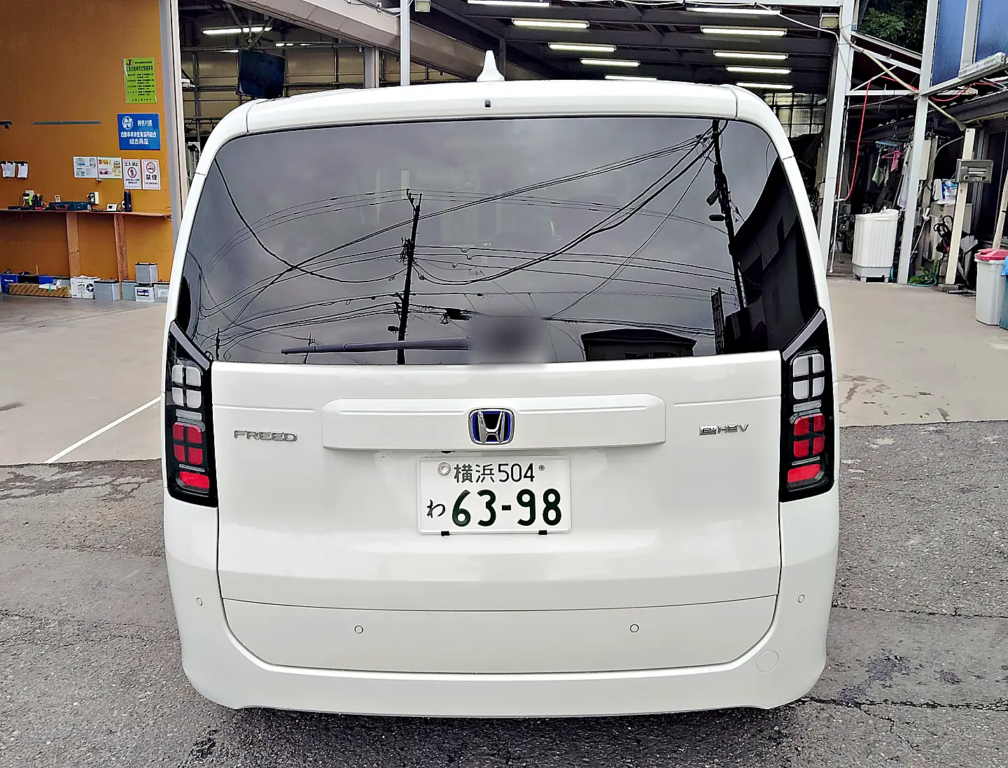 パールホワイトのフリード e:HEV の真後ろ。テールゲートの「FREED」の文字と「e:HEV」のエンブレム