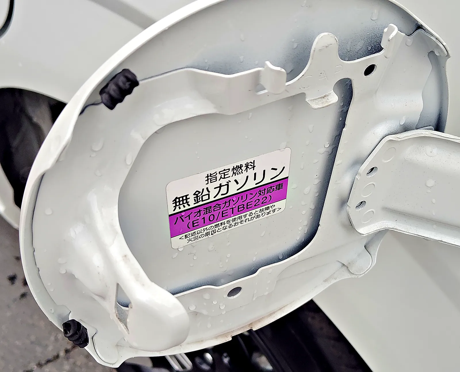 パールホワイトのフリード e:HEV の給油口のふたの裏。「指定燃料 無鉛ガソリン」の表示
